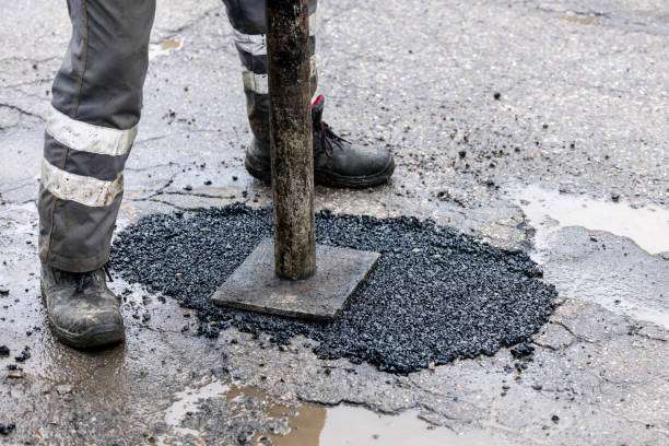 worker pushing bitumen asphalt in the hole. road repair and maintenance