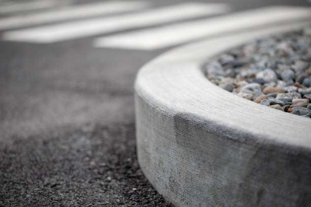 A curb with an asphalt road and a rock garden on the sides